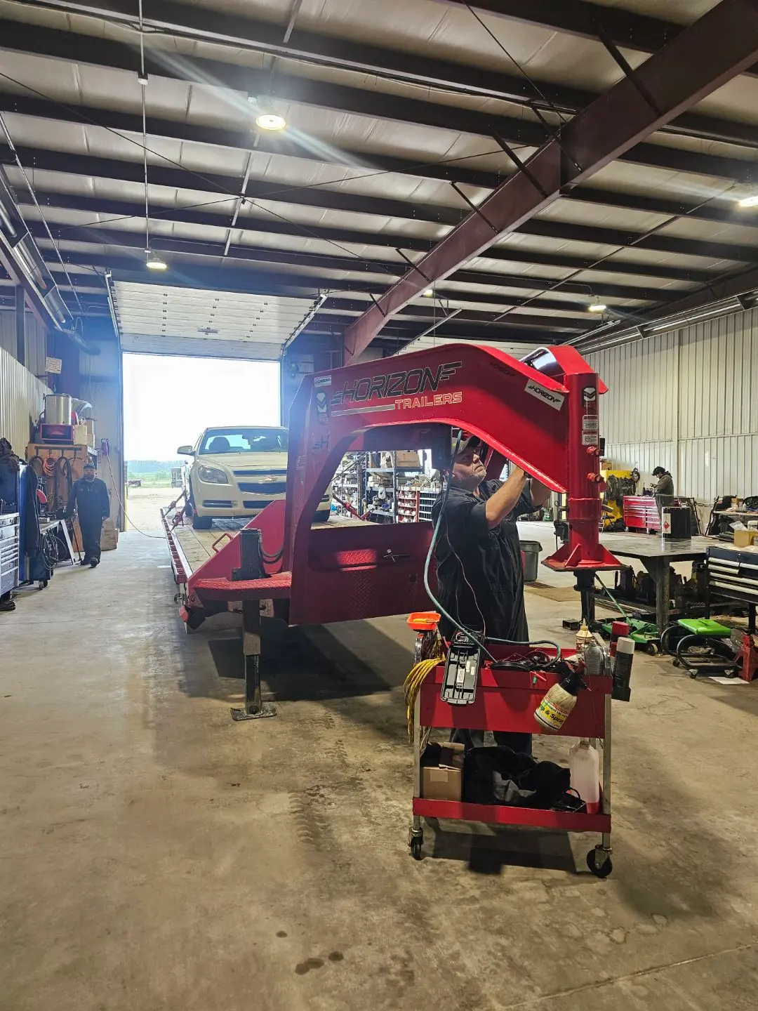 Tech under the raised gooseneck, staff working in background
